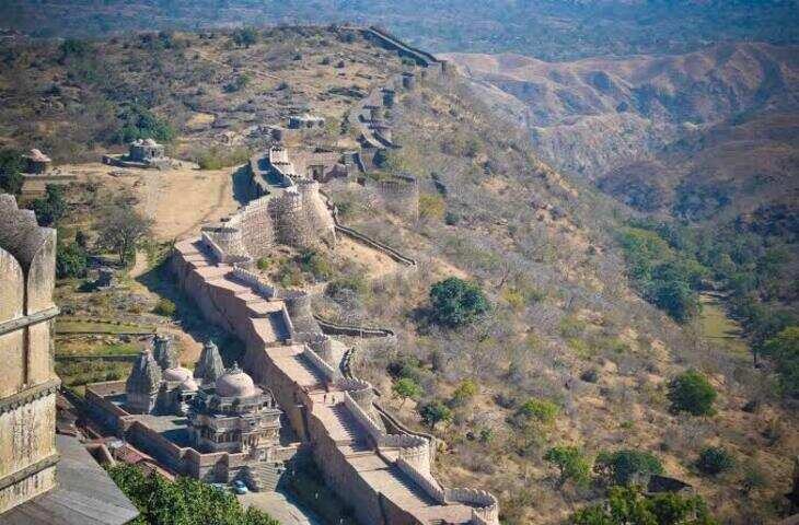 राजस्थान के राजसमंद जिले में अरावली की ऊंची पहाड़ियों के बीच स्थित कुंभलगढ़ दुर्ग राजस्थान के सबसे प्रसिद्ध ऐतिहासिक किलों में शामिल है। अपनी विशाल प्राचीर, मजबूत सुरक्षा व्यवस्था और स्थापत्य कला के कारण यह किला सदियों से लोगों के आकर्षण का केंद्र रहा है। इसे मेवाड़ की सैन्य शक्ति और राजपूत स्थापत्य का महत्वपूर्ण प्रतीक माना जाता है। कुंभलगढ़ को उसकी विशाल दीवार के कारण कई बार &lsquo;भारत की महान दीवार&rsquo; भी कहा जाता है। इसकी प्राचीर लगभग 36 किलोमीटर तक फैली हुई बताई जाती है। कई स्थानों पर दीवार इतनी चौड़ी है कि उस पर एक साथ कई घोड़े चल सकते थे।  महाराणा कुंभा ने कराया था निर्माण कुंभलगढ़ दुर्ग का वर्तमान स्वरूप मेवाड़ के शासक महाराणा कुंभा के शासनकाल में विकसित हुआ। इतिहासकारों के अनुसार किले के निर्माण का प्रमुख चरण 15वीं शताब्दी में हुआ। इसका निर्माण मेवाड़ की सुरक्षा को मजबूत करने और रणनीतिक दृष्टि से महत्वपूर्ण क्षेत्र पर नियंत्रण बनाए रखने के उद्देश्य से कराया गया था।अरावली की ऊंची पहाड़ियों पर स्थित होने के कारण किले को प्राकृतिक सुरक्षा भी प्राप्त थी। दुर्ग की ऊंचाई और मजबूत दीवारों ने इसे बाहरी हमलों से बचाने में महत्वपूर्ण भूमिका निभाई।  महाराणा प्रताप की जन्मभूमि कुंभलगढ़ का नाम मेवाड़ के महान योद्धा महाराणा प्रताप से भी गहराई से जुड़ा हुआ है। महाराणा प्रताप का जन्म 9 मई 1540 को कुंभलगढ़ में हुआ था। यही कारण है कि यह दुर्ग राजस्थान के इतिहास और राजपूत गौरव में विशेष स्थान रखता है।महाराणा प्रताप ने मुगल सम्राट अकबर के खिलाफ मेवाड़ की स्वतंत्रता के लिए लंबे समय तक संघर्ष किया। उनके जीवन से जुड़े इस किले के कारण कुंभलगढ़ देशभर के इतिहास प्रेमियों के लिए खास महत्व रखता है।  अभेद्य सुरक्षा व्यवस्था किले में कई विशाल प्रवेश द्वार बनाए गए थे। राम पोल, हनुमान पोल और पाघरा पोल जैसे द्वार इसकी सुरक्षा व्यवस्था का हिस्सा थे। किले के भीतर महल, मंदिर, जलाशय और सैनिकों के रहने की व्यवस्थाएं भी थीं।कुंभलगढ़ परिसर में बड़ी संख्या में मंदिर होने की जानकारी मिलती है। इनमें हिंदू और जैन परंपरा से जुड़े मंदिर शामिल हैं। इससे उस दौर की धार्मिक और स्थापत्य विविधता का भी पता चलता है।  विशाल प्राचीर है सबसे बड़ी पहचान कुंभलगढ़ की सबसे खास पहचान इसकी विशाल प्राचीर है। करीब 36 किलोमीटर लंबी दीवार पहाड़ियों के उतार-चढ़ाव के साथ किले को चारों ओर से घेरती है। दीवार के कई हिस्से आज भी काफी मजबूत स्थिति में दिखाई देते हैं।इसी विशाल दीवार की तुलना अक्सर चीन की महान दीवार से की जाती है। हालांकि दोनों की लंबाई और निर्माण का उद्देश्य अलग है, लेकिन कुंभलगढ़ की प्राचीर अपने आप में अद्भुत स्थापत्य उपलब्धि है।  आज प्रमुख पर्यटन स्थल आज कुंभलगढ़ राजस्थान के प्रमुख पर्यटन स्थलों में शामिल है। किले से अरावली पर्वतमाला का शानदार दृश्य दिखाई देता है। शाम के समय होने वाला लाइट एंड साउंड शो भी पर्यटकों के आकर्षण का केंद्र है।कुंभलगढ़ दुर्ग केवल पत्थरों से बनी एक ऐतिहासिक इमारत नहीं है, बल्कि यह मेवाड़ की सैन्य रणनीति, राजपूत वीरता और राजस्थान की स्थापत्य विरासत की कहानी कहता है। महाराणा कुंभा से लेकर महाराणा प्रताप तक, इस दुर्ग की दीवारों में मेवाड़ के गौरवशाली इतिहास की अनेक परतें आज भी दिखाई देती हैं।