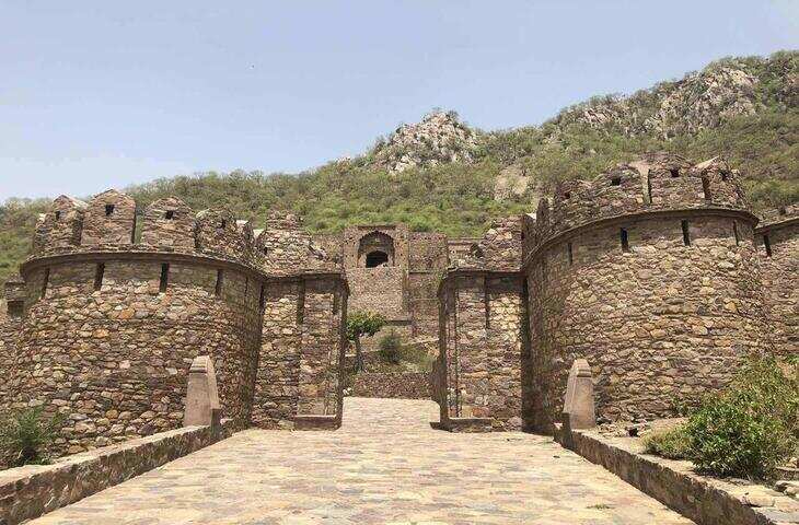 राजस्थान के अलवर जिले में अरावली की पहाड़ियों के बीच स्थित भानगढ़ किला भारत की सबसे चर्चित ऐतिहासिक और रहस्यमयी जगहों में गिना जाता है। वीरान गलियां, पुराने मंदिर, टूटे महल और चारों ओर फैली पहाड़ियां इस स्थान को बेहद आकर्षक बनाती हैं। इतिहास और लोककथाओं के कारण भानगढ़ आज देश-विदेश के पर्यटकों के लिए खास आकर्षण है।  आमेर के राजा ने बसाया था भानगढ़  भानगढ़ के निर्माण का श्रेय आमेर के शासक राजा माधो सिंह को दिया जाता है। माना जाता है कि उन्होंने 16वीं शताब्दी के उत्तरार्ध में यहां नगर बसाया था। किले के आसपास कभी एक समृद्ध बस्ती हुआ करती थी, जहां बाजार, मंदिर, हवेलियां और राजपरिवार से जुड़े भवन मौजूद थे।  भानगढ़ परिसर में आज भी कई प्राचीन मंदिरों के अवशेष दिखाई देते हैं। गोपीनाथ मंदिर, सोमेश्वर मंदिर, केशव राय मंदिर और हनुमान मंदिर इसकी ऐतिहासिक पहचान का हिस्सा हैं।  किले से जुड़ी दो प्रसिद्ध कहानियां  भानगढ़ की सबसे बड़ी पहचान इसकी रहस्यमयी कहानियां हैं। हालांकि इन कहानियों के सभी हिस्सों की ऐतिहासिक पुष्टि नहीं हुई है, लेकिन स्थानीय लोककथाओं में इनका जिक्र लंबे समय से होता रहा है।  एक प्रसिद्ध कहानी बालूनाथ योगी से जुड़ी है। कहा जाता है कि उन्होंने भानगढ़ बसाने की अनुमति इस शर्त पर दी थी कि किले की परछाईं उनके आश्रम से आगे नहीं जानी चाहिए। लोककथा के अनुसार, जब किले का विस्तार हुआ और उसकी छाया आश्रम तक पहुंची तो भानगढ़ पर संकट आ गया।  दूसरी कहानी एक तांत्रिक सिंहिया से जुड़ी है। लोककथा के मुताबिक, वह भानगढ़ की राजकुमारी रत्नावती पर मोहित था। उसने कथित तौर पर राजकुमारी को अपने वश में करने की कोशिश की, लेकिन उसकी योजना सफल नहीं हुई। इसके बाद उसने भानगढ़ को श्राप देने की बात कही जाती है।  अचानक उजड़ गया भानगढ़  लोकप्रिय मान्यता के अनुसार, किसी श्राप के बाद भानगढ़ धीरे-धीरे उजड़ गया। हालांकि इतिहासकारों के अनुसार, भानगढ़ के उजड़ने के पीछे युद्ध, राजनीतिक परिस्थितियां, पानी की कमी और आर्थिक कारणों सहित कई संभावित वजहें हो सकती हैं।  17वीं और 18वीं शताब्दी के बाद यहां की आबादी कम होती गई और कभी चहल-पहल से भरा नगर खंडहरों में बदल गया।  रात में प्रवेश पर प्रतिबंध क्यों?  भानगढ़ को लेकर सबसे ज्यादा चर्चा सूर्यास्त के बाद प्रवेश को लेकर होती है। भारतीय पुरातत्व सर्वेक्षण यानी ASI की ओर से यहां सूर्यास्त से सूर्योदय तक पर्यटकों के प्रवेश पर प्रतिबंध लगाया गया है।  इसी नियम को लेकर भानगढ़ के बारे में कई डरावनी कहानियां प्रचलित हैं। स्थानीय लोगों में यह मान्यता भी सुनने को मिलती है कि रात में यहां असामान्य घटनाएं होती हैं। हालांकि इन दावों का कोई ठोस वैज्ञानिक प्रमाण नहीं है।  इतिहास और रहस्य का अनोखा संगम  आज भानगढ़ किला इतिहास, वास्तुकला और लोककथाओं में रुचि रखने वाले लोगों के लिए बेहद खास जगह है। किले के खंडहरों के बीच बने मंदिर, महल और बाजार के अवशेष राजस्थान के मध्यकालीन नगर जीवन की झलक देते हैं।  भानगढ़ की असली खूबसूरती शायद इसी विरोधाभास में है&mdash;एक तरफ समृद्ध इतिहास और स्थापत्य, दूसरी तरफ सदियों पुरानी रहस्यमयी लोककथाएं। यही वजह है कि राजस्थान आने वाले पर्यटकों की सूची में भानगढ़ किले का नाम आज भी प्रमुखता से शामिल रहता है।